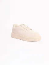Championes de plataforma baja de color beige, con cordones tono sobre tono y detalle de placa metálica en los cordones.