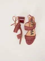 Sandalias de gamuza color bordó con taco bloque de charol, tiras con pespuntes artesanales en cuero y tira fina ajustable al tobillo.