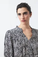 Camisa de manga larga color marrón con estampado de lunares blancos, cuello mao y cierre frontal con botones.