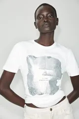 Camiseta blanca de manga corta y cuello redondo, con detalle de estampa central metalizada de efecto texturizado y diseño regular fit.