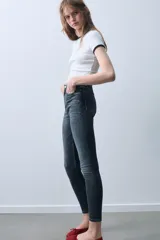 Jeans skinny de tiro alto en color negro, confeccionados en tejido super elástico de cinco bolsillos, con cierre frontal de cremallera y botón metálico.