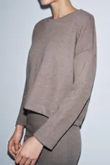 Top de tejido soft con cuello redondo, manga larga y bajo recto.
