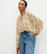 Blusa manga larga verde oliva con estampado paisley y floral en tonos blancos y morados, con escote redondo fruncido y cordones para atar en el frente.
