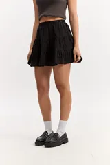 Falda corta blanca con volados en capas, confeccionada en tejido de algodón con bordado estilo broderie. Cuenta con cintura elástica.