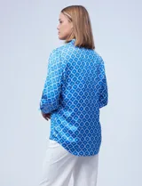 Camisa de satén estampado en blanco y negro, con cuello con solapa, escote en V y abertura central con botones.