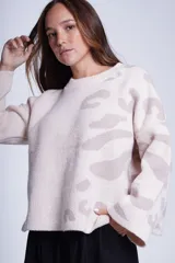 Sweater de punto color crema con estampado animal print en tonos beige. Tiene cuello redondo y mangas largas acampanadas.
