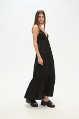 Vestido largo negro de breteles finos, escote en V pronunciado con detalle de argolla central, y cuerpo con punto smock. Falda amplia y holgada con tajo lateral.