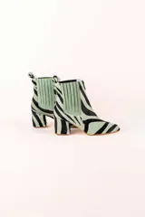 Botines de cuero con estampado de cebra en tonos verde claro y negro, con puntera fina y tacón cuadrado. Presentan paneles laterales elásticos en color verde liso.