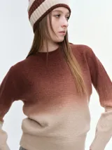 Buzo tejido de punto con diseño degradé que transiciona de azul oscuro a celeste claro. Presenta cuello redondo, mangas largas y puños acanalados, con un corte holgado y relajado.