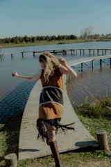 Vestido corto marrón con detalles en negro y flecos en el ruedo. Confeccionado artesanalmente con diferentes cueros bordados a mano y espalda en tejido de hilado.