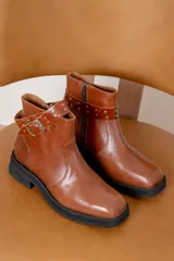 Bota corta de cuero azul con suela track negra, detalle de tira con hebilla metálica y tachas decorativas en el tobillo.
