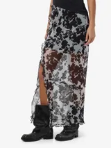 Pollera larga de tiro alto confeccionada en tejido liviano con estampa animal print tipo vaca, tajo frontal y detalles de volados en los bordes.