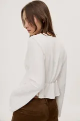 Blusa manga larga de color negro con escote en V profundo y lazo ajustable en el frente, confeccionada en tejido liviano con corte evasé.