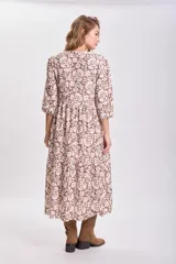 Vestido largo de corte holgado con diseño de paneles escalonados, estampado floral en tonos marrón y beige, cuello redondo y mangas tres cuartos abullonadas.