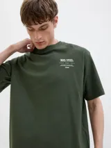 Remera verde militar de manga corta, con cuello redondo y diseño holgado. Cuenta con un pequeño estampado tipográfico en el pecho.