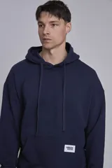Buzo hoodie azul marino de algodón con corte holgado, capucha con cordones ajustables, bolsillo tipo canguro y etiqueta con logo en el frente.