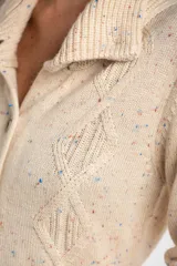 Cardigan beige con diseño de rombos en relieve, cuello con solapa y cierre frontal con botones.