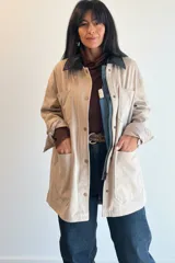 Campera de ecocuero color chocolate, con diseño amplio y relajado. Presenta cuello camisero, cierre frontal con cremallera y botones a presión, además de bolsillos delanteros amplios.