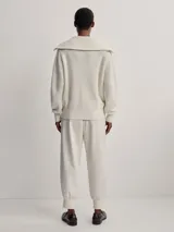 Campera larga tejida color crema con cierre frontal, cuello alto y diseño texturizado.