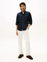 Camisa de manga larga color azul marino, confeccionada en algodón BCI con tecnología non-iron. Presenta cuello clásico, cierre frontal de botones blancos y el logo de Tommy Hilfiger bordado en el pecho.