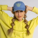 Gorro tipo cap de color azul con visera curva y bordado frontal en color amarillo con la frase 'HAVE A GOOD DAY'.