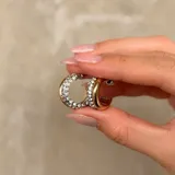 Aros tipo argolla de diseño bicolor, con una mitad en metal dorado liso y la otra mitad pavimentada con cristales brillantes.