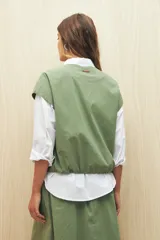 Chaleco color beige sin mangas de silueta relajada, con escote redondeado, cierre frontal con cremallera y ruedo elastizado.