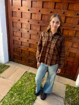 Camisa de manga larga con estampado de cuadros escoceses en tonos marrones. Presenta cuello clásico, cierre frontal con botones y corte holgado.