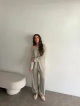 Conjunto gris melange compuesto por un buzo de cuello bote amplio y corte asimétrico con bolsillos, y un pantalón largo de corte recto y holgado.