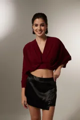 Blusa cropped de color bordó, con escote en V profundo, mangas largas con puños elásticos y diseño drapeado en el frente.