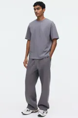 Remera gris de corte relajado, confeccionada en punto liviano con cuello redondo ribeteado, hombros caídos y mangas cortas.