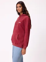 Canguro oversize color negro con efecto lavado, capucha y estampa gráfica en la espalda con tipografía desgastada y detalles en color turquesa.