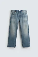 Jeans de mezclilla rígida de algodón, color azul claro con efecto lavado y ligero desgaste. De tiro medio, corte recto desde la cadera hasta la rodilla y ligeramente acampanado en el bajo (bootcut). Cierre frontal con botonadura y cinco bolsillos.