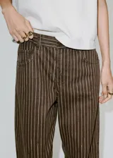 Jeans de corte recto y tiro medio, confeccionados en denim marrón con diseño de rayas verticales claras. Presenta bolsillos delanteros y traseros clásicos.