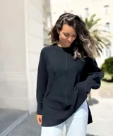 Sweater de punto color negro, con diseño oversize, cuello redondo, costura central vertical y aberturas laterales en el ruedo. Presenta mangas largas con puños acanalados.