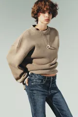 Jeans de tiro alto color marrón oscuro con acabado lavado, corte recto/flare y bajo cropped sin costuras. Presenta cinco bolsillos y cierre frontal con cremallera y botón metálico.