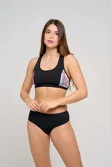 Top deportivo de natación negro con diseño de espalda nadadora, tirantes anchos fijos y detalles laterales con estampado colorido.