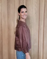 Camisa de manga larga con diseño de rayas verticales y bordados sutiles. Presenta cuello redondo, cierre frontal con botones y mangas abullonadas con volados en los hombros.