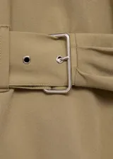 Blusa sin mangas color beige con cuello perkins y hombreras marcadas. Presenta un diseño recto con cinturón ajustable integrado en la cintura y cierre de cremallera en la parte posterior.