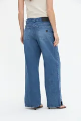 Jean wide leg color azul medio, con amplitud de piernas y tajo en el bajo.