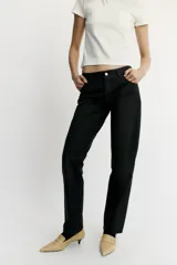 Jeans de tiro bajo y corte recto holgado, con efecto encerado en color negro, cinco bolsillos y trabillas para cinturón. Cierre frontal con cremallera y botón metálico.