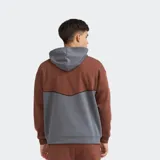 Canguro oversize de felpa con capucha, combinado en color marrón y gris, con bolsillo tipo canguro y pequeño estampado frontal.