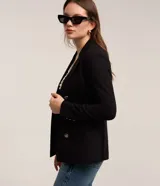 Blazer femenino de sastrería confeccionado en punto roma, con cuello solapa, cierre frontal con botones decorativos y diseño estructurado.