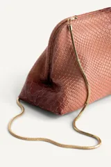 Bolso tipo pouch con textura de piel de serpiente en tonos degradados de rosado y bordó. Cuenta con una cadena dorada extraíble y cierre superior mediante clip.