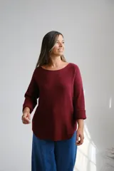 Sweter de punto color bordo, con escote a la base y mangas largas con puños doblados.