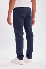 Pantalón estilo chino en color azul marino, confeccionado con tejido que incluye elastano para mayor comodidad y libertad de movimiento. Presenta un corte clásico y ajuste cómodo.