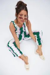 Pantalón de corte recto y tiro medio-alto, confeccionado en tela crepé con estampado geométrico de bloques en tonos verde, lila y blanco. Cuenta con pretina, cierre frontal y botón.