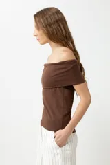 Remera de color marrón con escote bardot, diseño ajustado al cuerpo y mangas cortas.