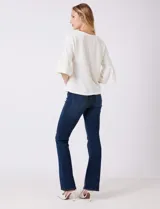 Buzo tejido de punto fino color blanco, con cuello redondo y mangas tres cuartos con terminación acampanada.