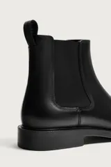 Bota tipo chelsea de piel lisa con elásticos laterales y horma redonda. Cuenta con suela de goma con ligero tacón y tirador trasero.